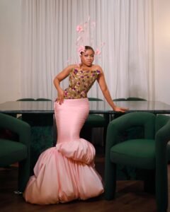 Veekee James holding a grape cluster prop in a custom Veekee James brand pink mermaid gown with puffed hem for baby Eliana Atere Fruit Garden reception theme