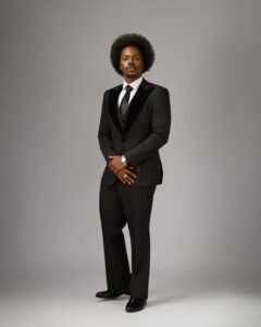 Full-length photo of Enioluwa Adeoluwa in a black three-piece tuxedo and patent leather shoes.