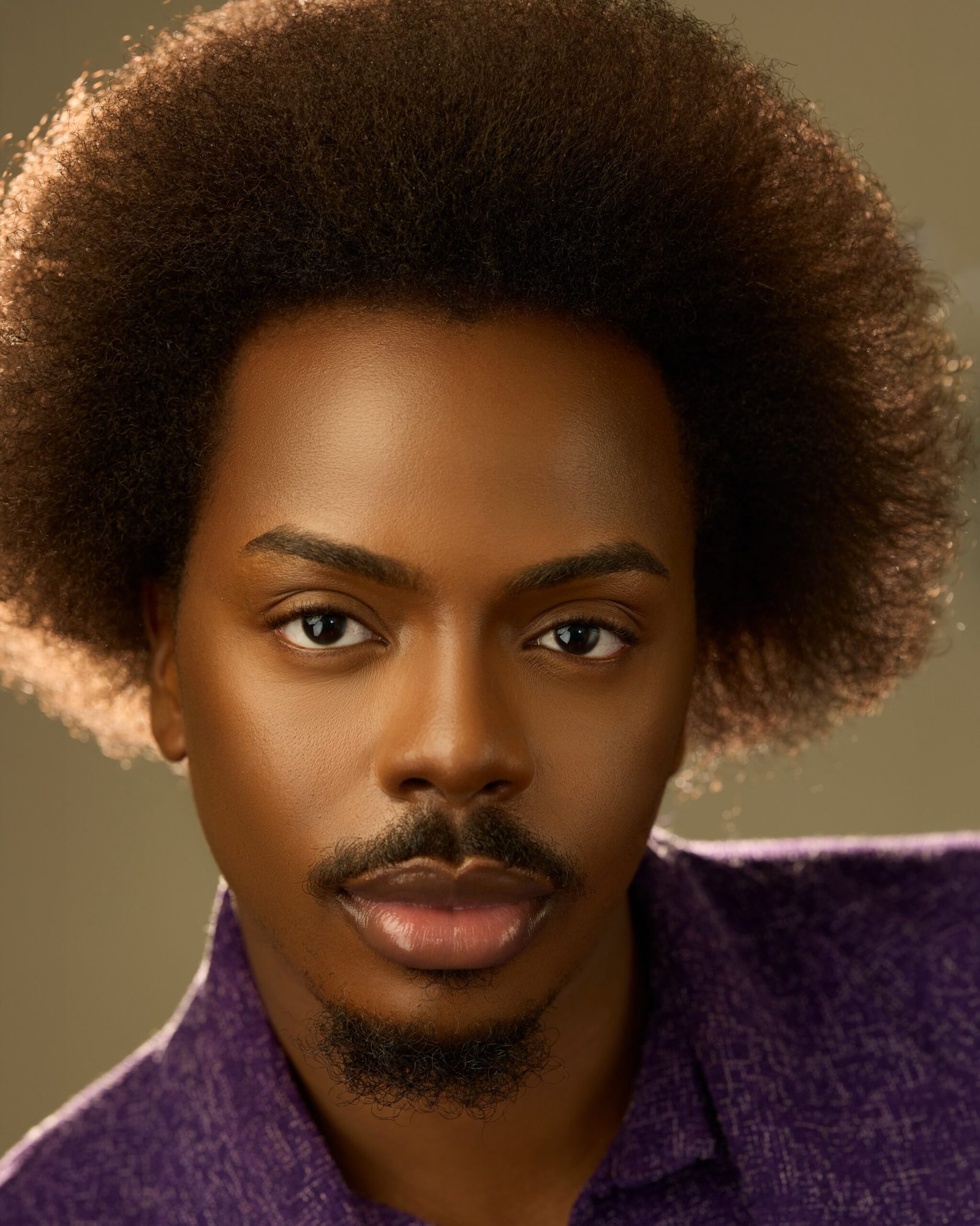 headshot of Enioluwa Adeoluwa showcasing a rounded Afro and trimmed goatee in a textured purple shirt.