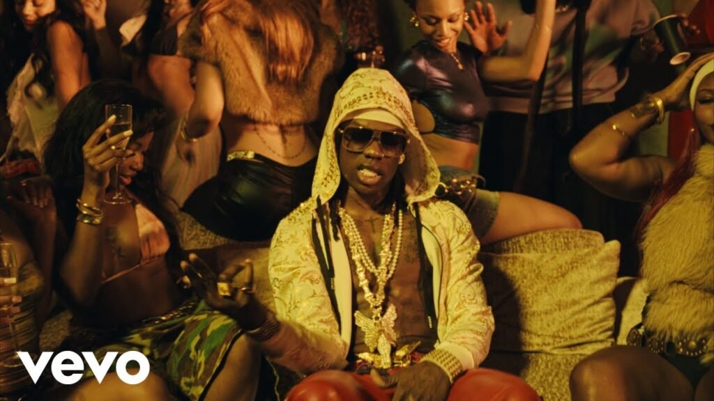 Mavin Records artist Rema wearing a pattern-patterned hooded jacket, sunglasses, and layered gold butterfly necklaces in a scene from his official TEA music video.