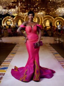 Bozoma Saint John and Keely Watson smiling at each other while walking in traditional hand-woven Kente drapes and gold jewellery.