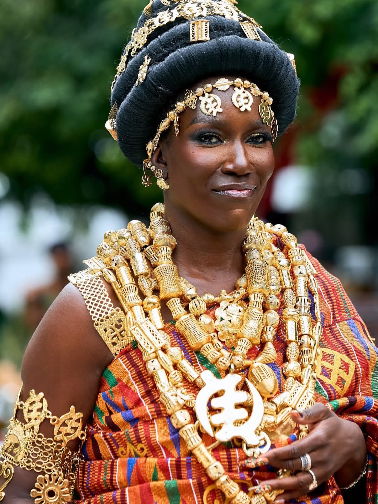 Bozoma Saint John wearing traditional Akan gold beaded necklaces, arm cuffs, Tikua headpiece, and hand-woven Kente drape.