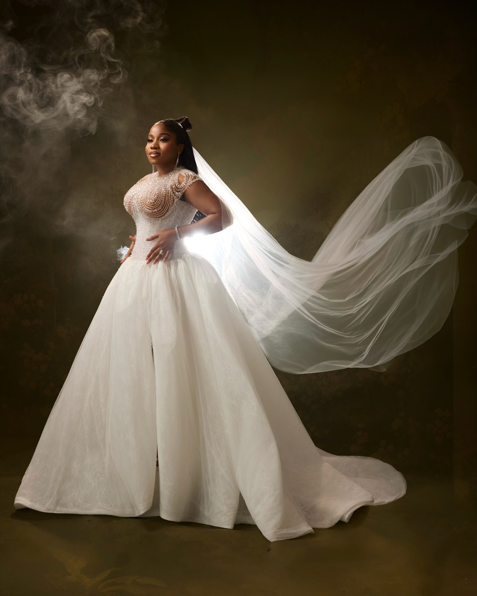 Veekee James posing in a custom white ballgown with a long billowing tulle veil