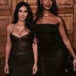 Tems in a black strapless dress posing beside Kim Kardashian in a brown leather corset dress at the SKIMS London event.