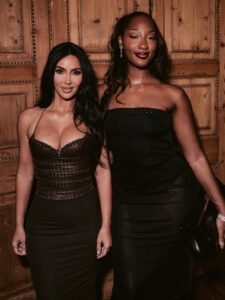 Tems in a black strapless dress posing beside Kim Kardashian in a brown leather corset dress at the SKIMS London event.
