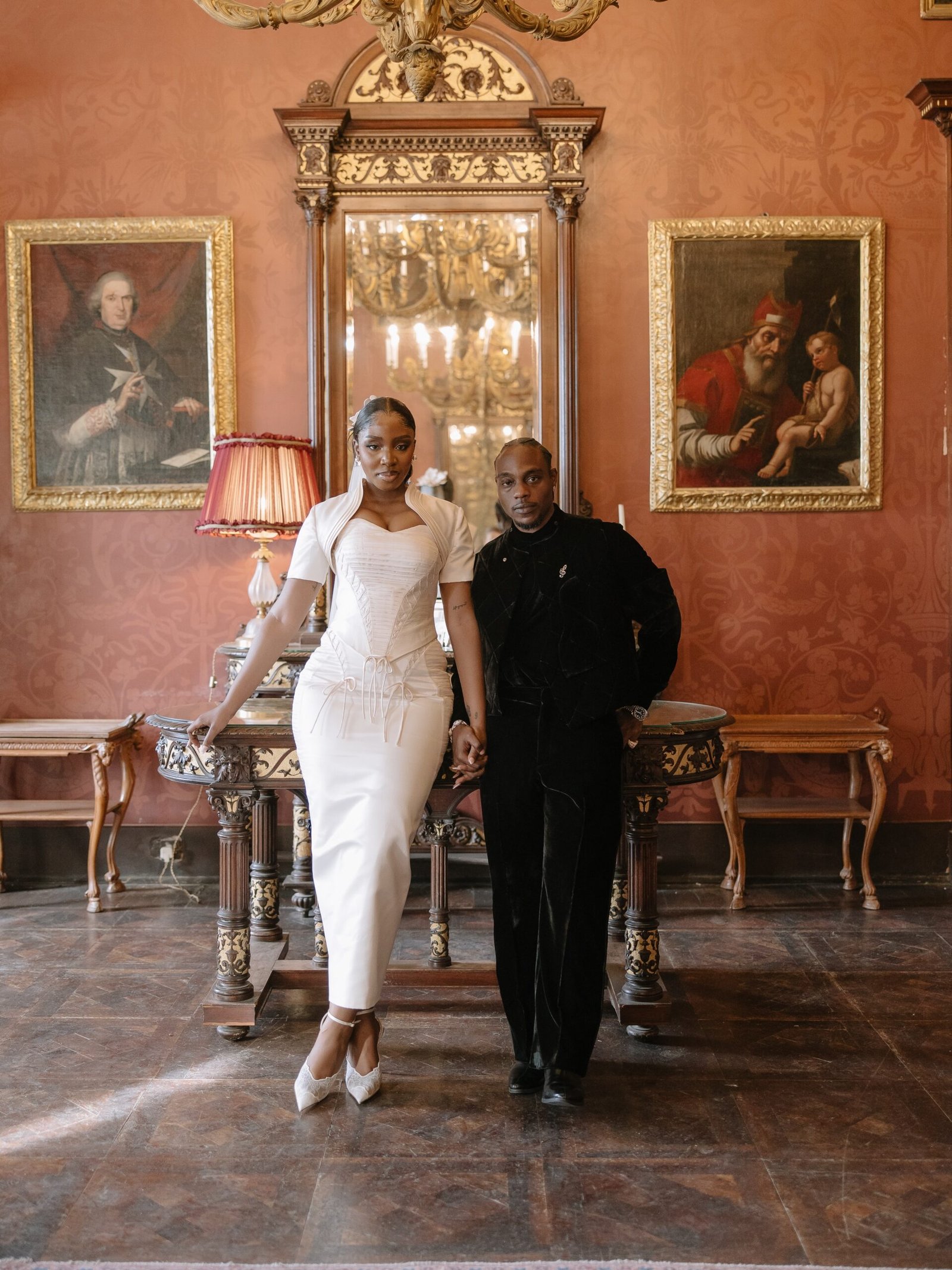 LAX and Ella holding hands inside a decorated historic room during their white wedding ceremony in Malta.