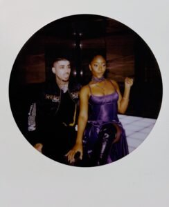 Zayn Malik sticking his tongue out next to Ayra Starr gesturing on a lit-up floor in a circular polaroid frame.