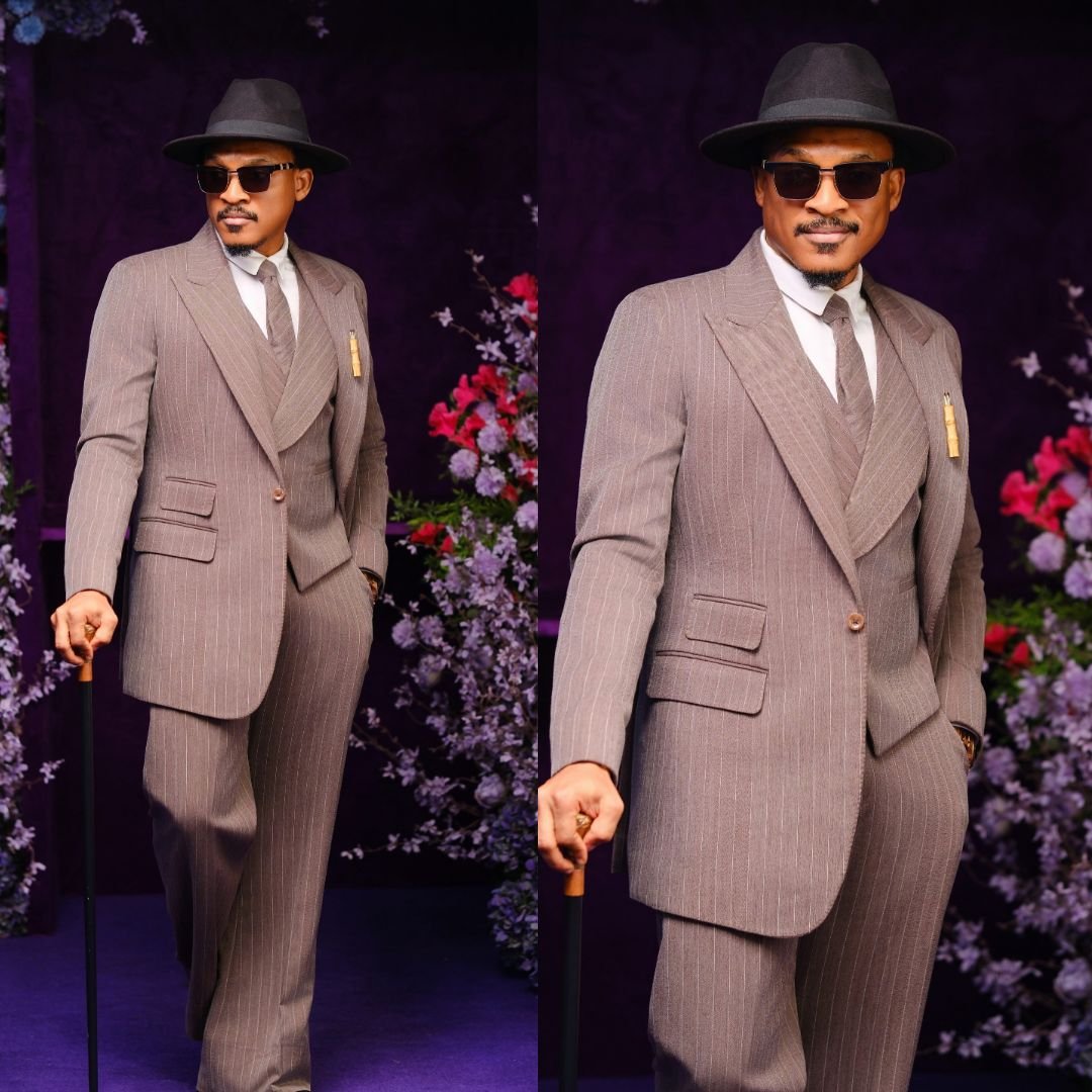 Shawn Faqua wearing a pinstriped three-piece suit, fedora hat, sunglasses, and holding a walking cane at BellaNaija Grand Red Carpet Experience.