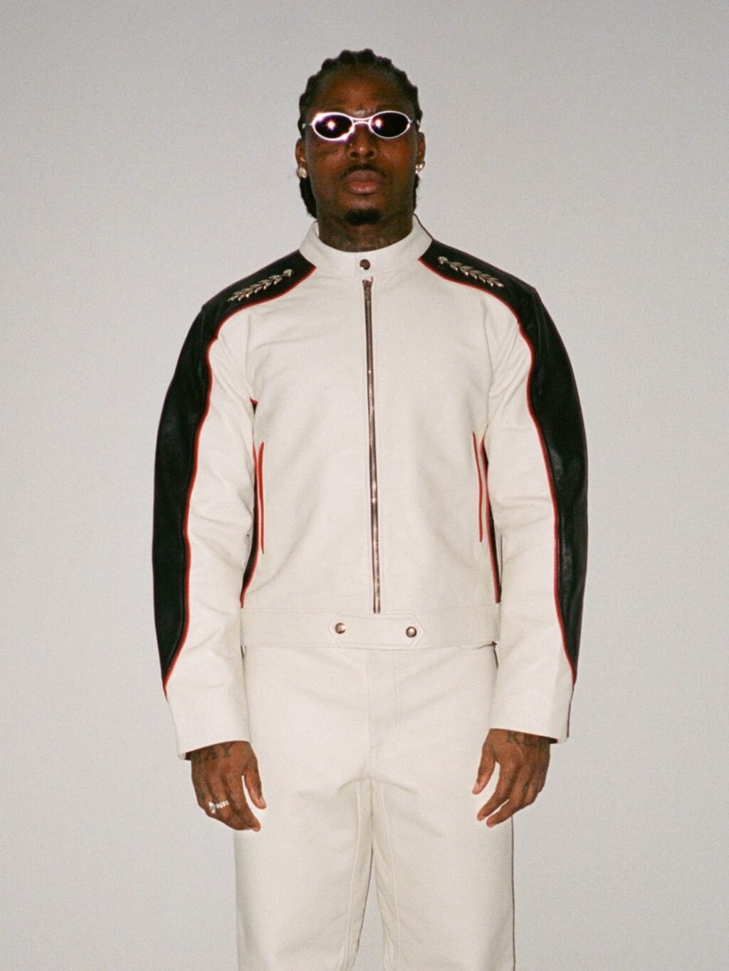Asake wearing a white and black leather biker suit with oval sunglasses reflecting his Mr Money persona.