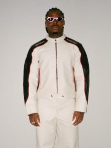 Asake wearing a white and black leather biker suit with oval sunglasses reflecting his Mr Money persona.