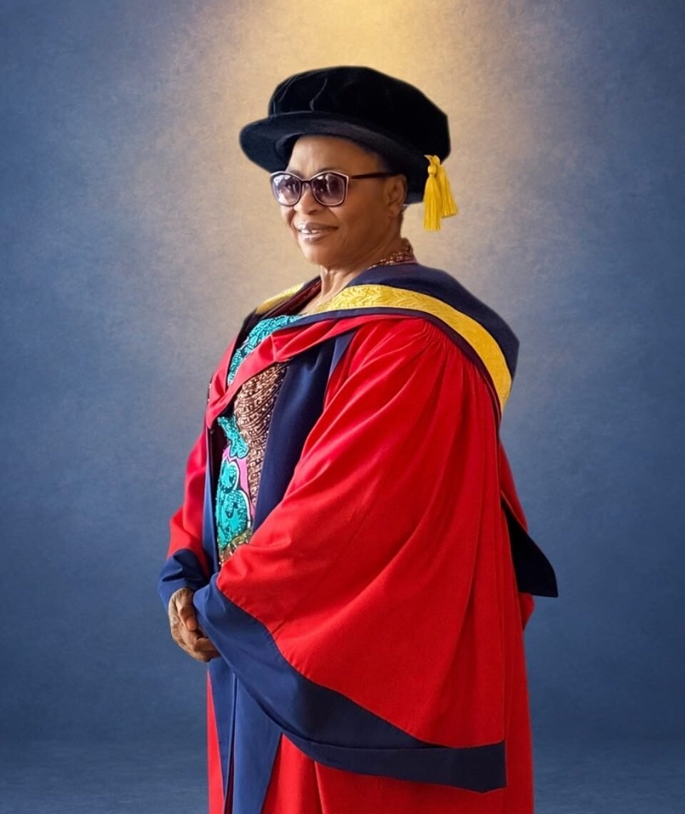 Folorunso Alakija wearing a red doctoral gown, black cap, and tinted glasses.